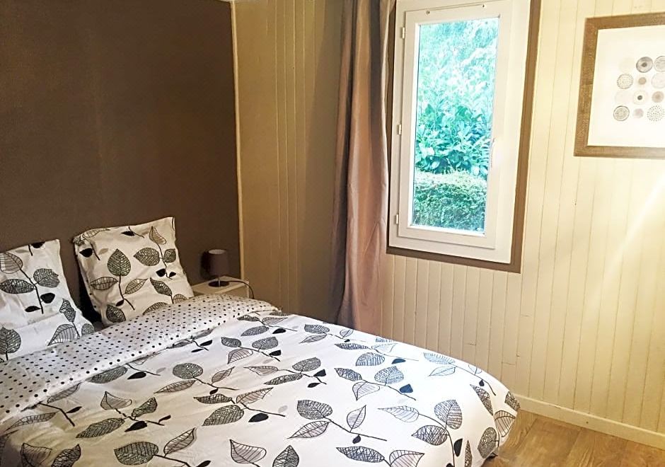 a cozy bedroom with a large window , a bed decorated with white and black bedding , and wooden floors at Le Bellevue