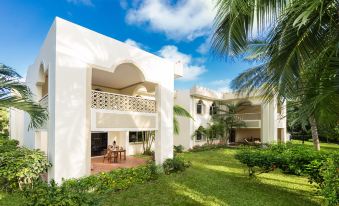 a white house with a courtyard in the front , surrounded by lush greenery and palm trees at Diamonds Dream of Africa