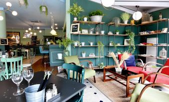 a dining area with a blue wall and shelves filled with potted plants , creating a cozy atmosphere at Ibis Nantes Saint-Herblain