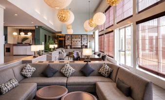 a modern living room with a large sectional couch , multiple chairs , and several lamps hanging from the ceiling at Element Lexington