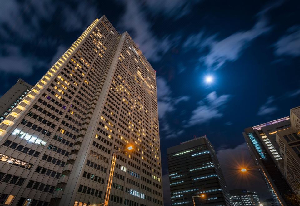 A tall, illuminated building in the city at night, viewed from a distance at Keio Plaza Hotel Tokyo