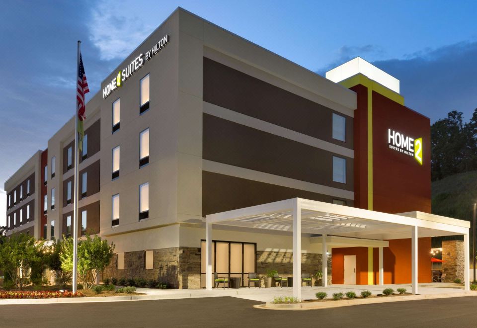 an exterior view of a hotel building with a large sign above the entrance , surrounded by trees and other buildings at Home2 Suites by HIlton Cartersville
