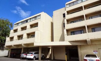 a modern , beige - colored apartment building with multiple balconies and cars parked in the parking lot at St Ives Apartments