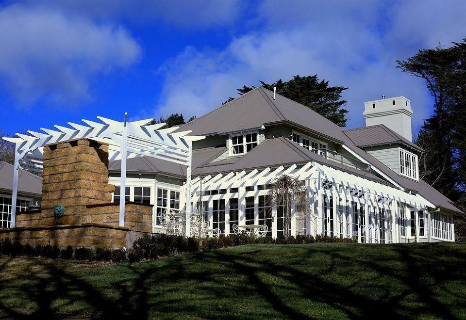 a large house with a white roof and white columns is surrounded by trees and grass at Parklands Country Gardens & Lodges Blue Mountains