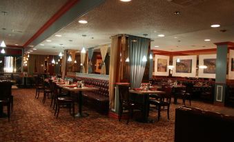 a dining room with several tables and chairs , some of which are covered with tablecloths at Plaza Hotel & Casino