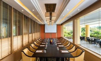 a conference room with a long table surrounded by chairs and a projector screen on the wall at Dusit Thani Pattaya