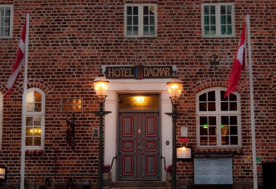 "a brick building with a red awning , featuring a door with a sign that reads "" hotel dagnn .""." at Hotel Dagmar