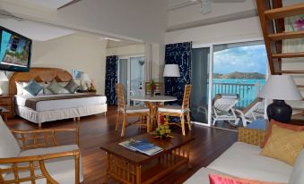 a bedroom with a bed , chairs , and a table near a sliding glass door leading to an ocean view at Grand Case Beach Club