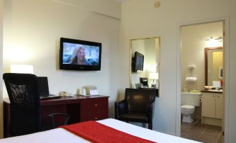 a hotel room with a tv on the wall , a bed with red and white bedding , and a desk in front of the bed at Hotel du Nord
