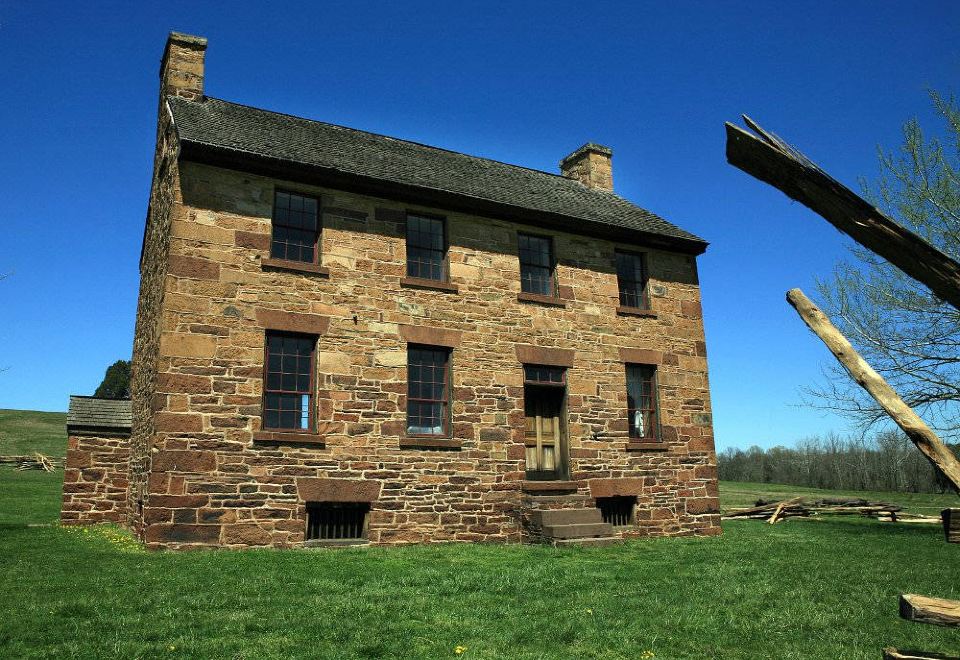 a large stone house with multiple windows and a grassy lawn in front of it at Courtyard Manassas Battlefield Park
