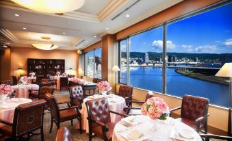 a dining room with tables and chairs arranged for a large group of people to enjoy a meal at Numazu River Side Hotel