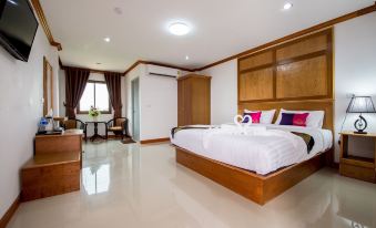 a large bed with white linens is in a room with wooden furniture and a window at Thatphanom View Hotel
