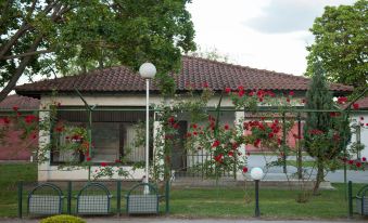 a house with a red roof and a white fence in front of it , surrounded by trees at Hotel Bellevue