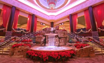 a large indoor fountain with red flowers and a waterfall in the center , surrounded by a room filled with chandeliers and red flowers at Mount Airy Casino Resort - Adults Only