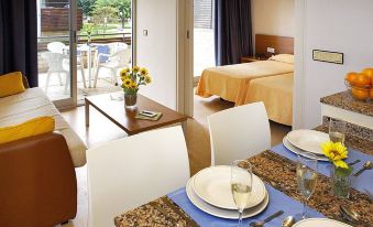 a dining table set with wine glasses , plates , and a vase of flowers in a hotel room at Aparthotel Comtat Sant Jordi