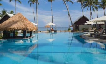 a resort with a large pool surrounded by palm trees , umbrellas , and a gazebo on the beach at Saletoga Sands Resort & Spa