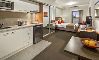 a kitchen and bedroom area in a hotel room , with a bed visible through a window at Quest Mildura