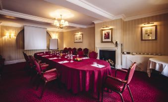 a conference room with a red carpet , chairs arranged in rows , and a large table surrounded by chairs at Small Luxury Hotels of the World - the Mitre Hampton Court