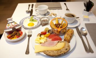 a table is set with a variety of food items , including bread , meat , cheese , and fruit at Hotel Carlton
