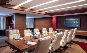 "a conference room with a wooden table , chairs , and a large screen displaying the word "" conference "" on it" at Burgu Arjaan by Rotana