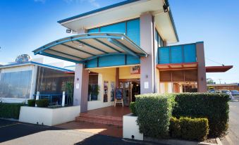 a blue and white building with a metal roof , situated on a dirt road under a clear sky at Wilsonton Hotel