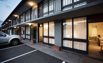 a parking lot with a car parked in front of a building with two floors at Nightcap at Matthew Flinders Hotel