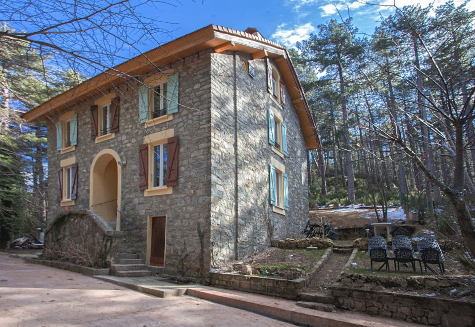 a stone house with wooden shutters and a wooden door , situated in a wooded area at Casa Alta