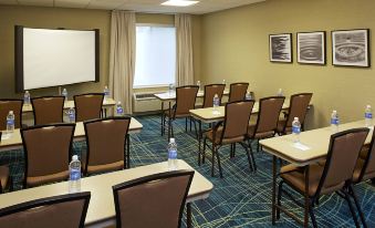 a conference room with rows of chairs and tables , water bottles on each table , and curtains at SpringHill Suites Atlanta Six Flags