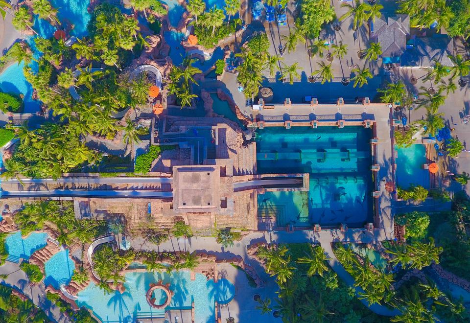 a bird 's eye view of a large resort with a pool , palm trees , and mountains at The Royal at Atlantis