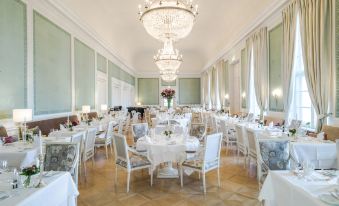 a large , elegant dining room with white tablecloths and chairs , a chandelier , and green walls at Grand Hotel Heiligendamm - the Leading Hotels of the World