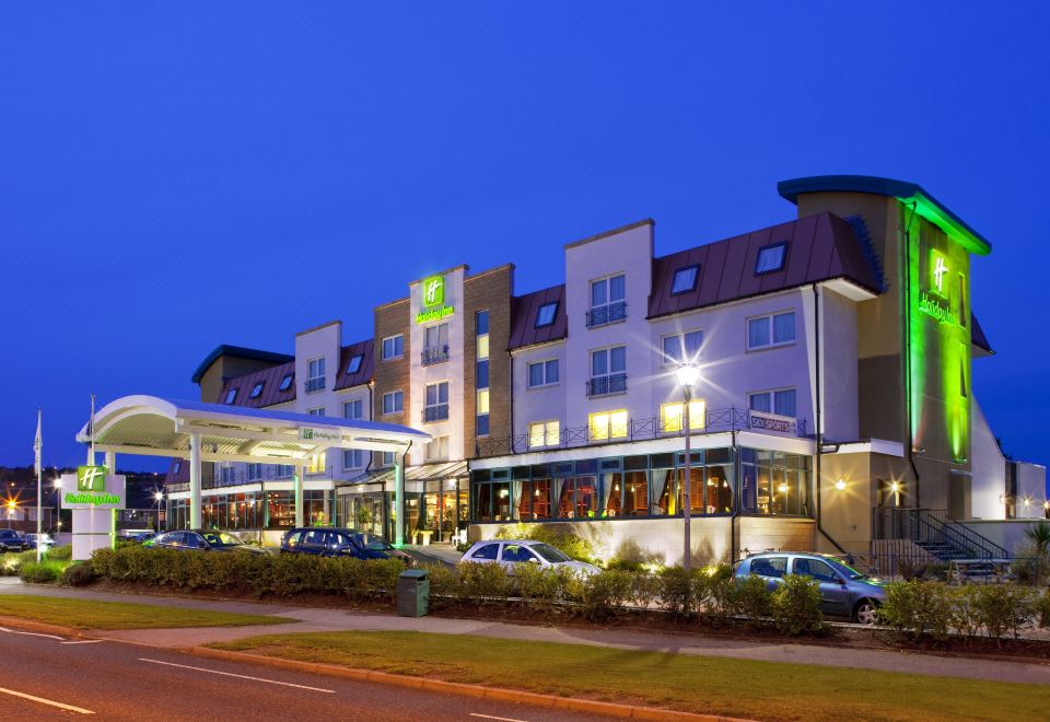 a large hotel building with a covered walkway and several cars parked in front of it at Holiday Inn Aberdeen - West