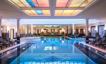 an indoor swimming pool with a glass ceiling , allowing natural light to illuminate the space at Althoff Seehotel Uberfahrt