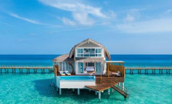 a house - shaped water villa with a hot tub on stilts over the ocean , surrounded by clear blue water at JW Marriott Maldives Resort & Spa