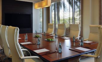 a conference room with a long wooden table , chairs , and large windows overlooking the city at Movenpick Hotel Bahrain