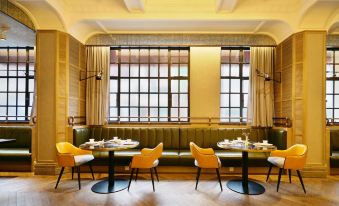 restaurant with ample natural light and centrally located tables, complemented by vibrant orange walls at Metropolo Jinjiang Hotel Classiq (Shanghai Nanjing Road Pedestrian Street)