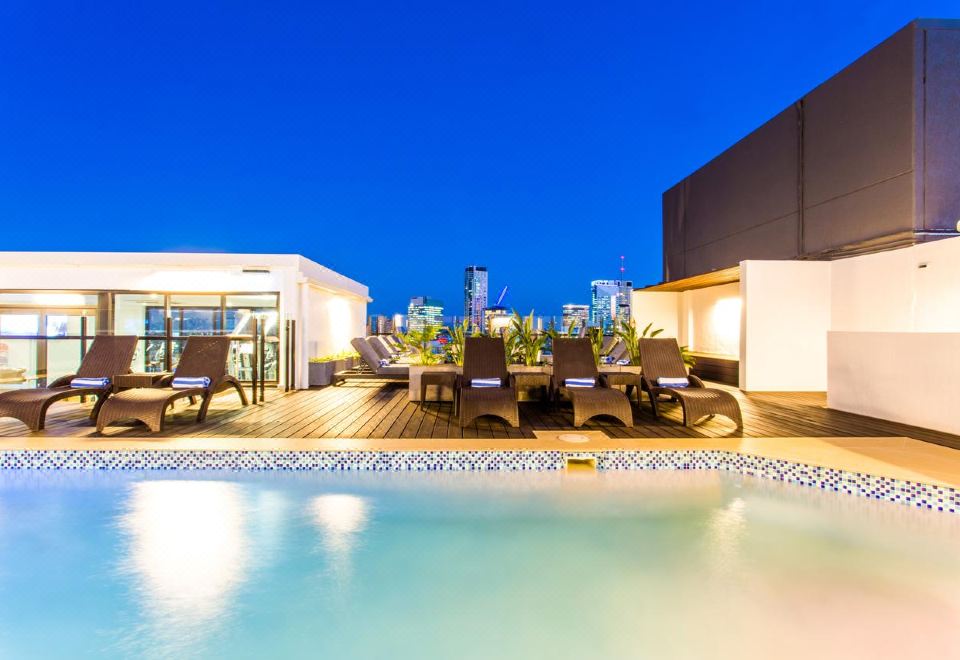 a rooftop pool area with several lounge chairs and a bar , providing a comfortable outdoor space for relaxation at Hotel Grand Chancellor Brisbane