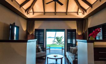 a modern living room with wooden ceiling , large windows offering views of the ocean , and comfortable seating arrangements at Matamanoa Island Resort