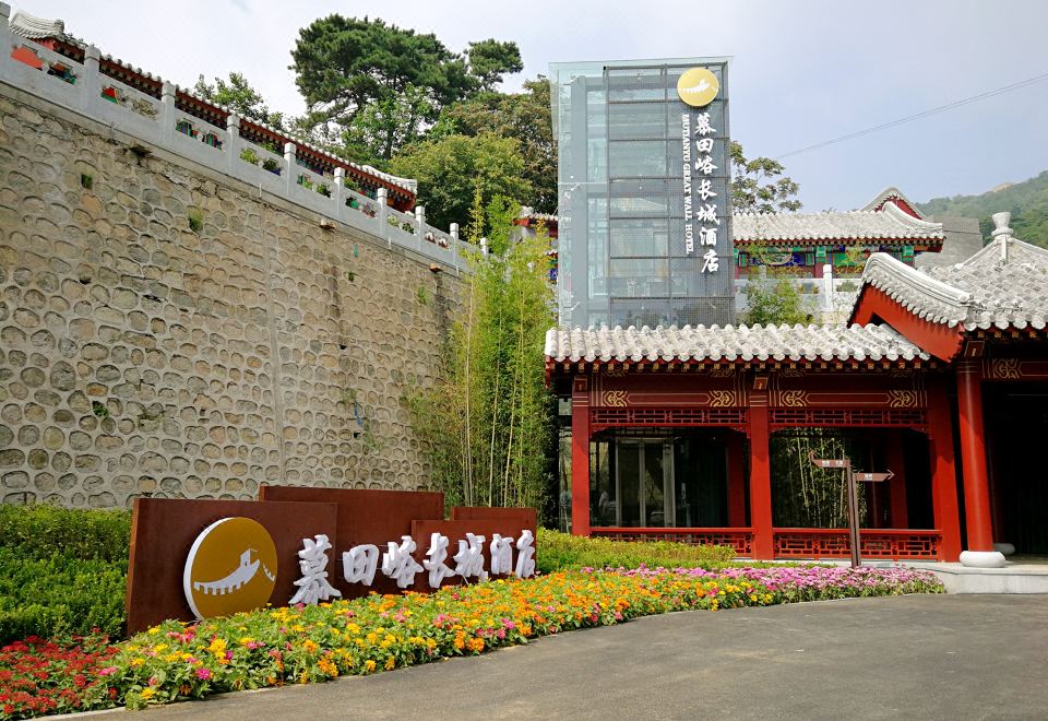 The entrance to a city is adorned with large buildings and flowers in front at Mutianyu Great Wall Hotel