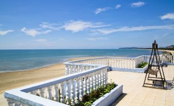 a white balcony with a view of the ocean , overlooking a sandy beach under a blue sky at Sanctuary Resort