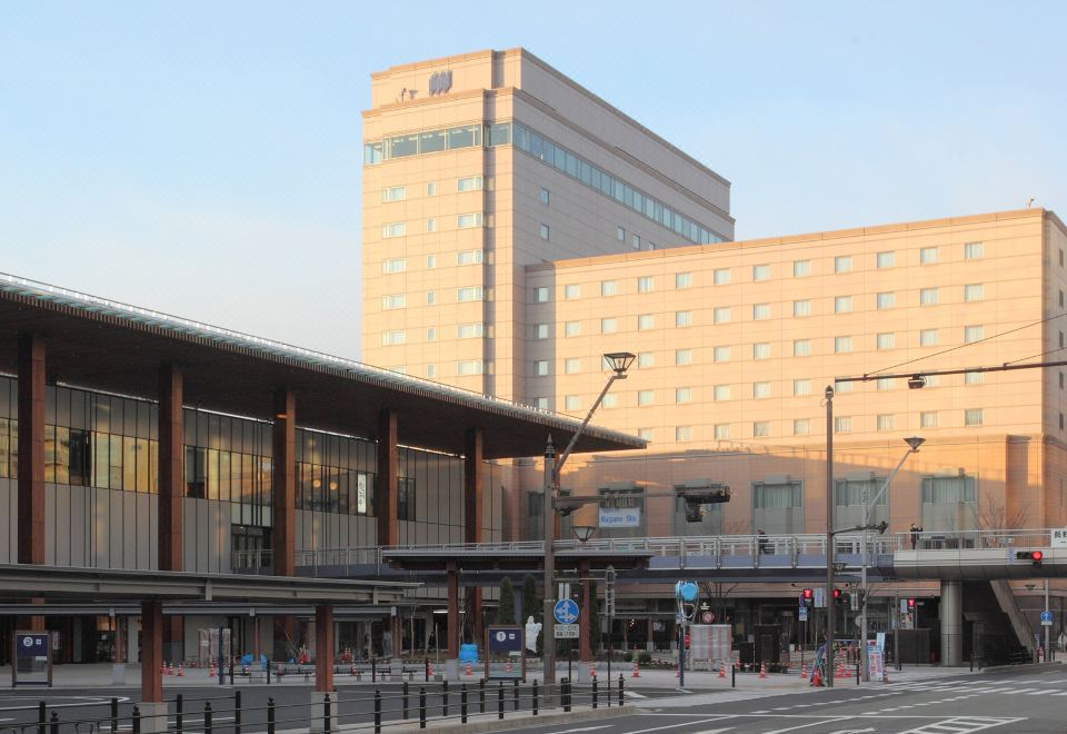 a large building with a clock on the side is next to a train station at Hotel Metropolitan Nagano