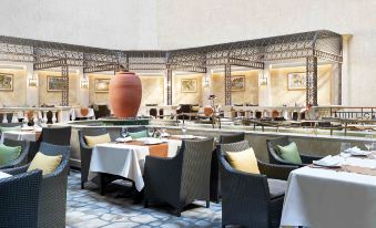 A restaurant with tables and chairs arranged in a circular formation in the center at The Royal Garden Hotel