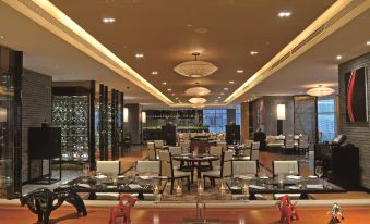 There is a restaurant in the middle of the hotel with tables and chairs, as well as other rooms at Sofitel Guangzhou Sunrich