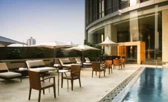 There is an outdoor restaurant or hotel with a pool area that includes tables and chairs at the Westin Guangzhou