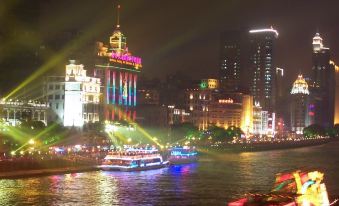 A city illuminated at night with boats on the water and buildings on both sides at Na Fang Da Sha Hotel