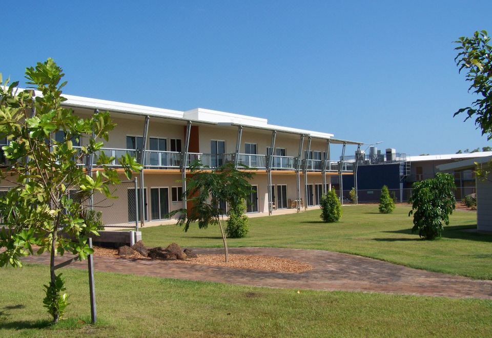 a modern , white apartment building with balconies and a green lawn , under a clear blue sky at Club Tropical Resort Darwin