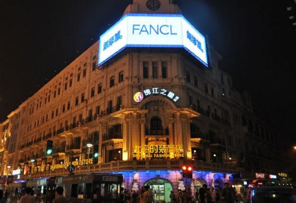 A large Asian building is illuminated at night, bustling with people and lights at Jinjiang Inn Select (Shanghai Nanjing Road Pedestrian Street)