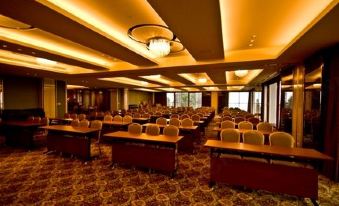 a large conference room with rows of chairs and tables , a chandelier hanging from the ceiling , and windows on one side at Alishan House