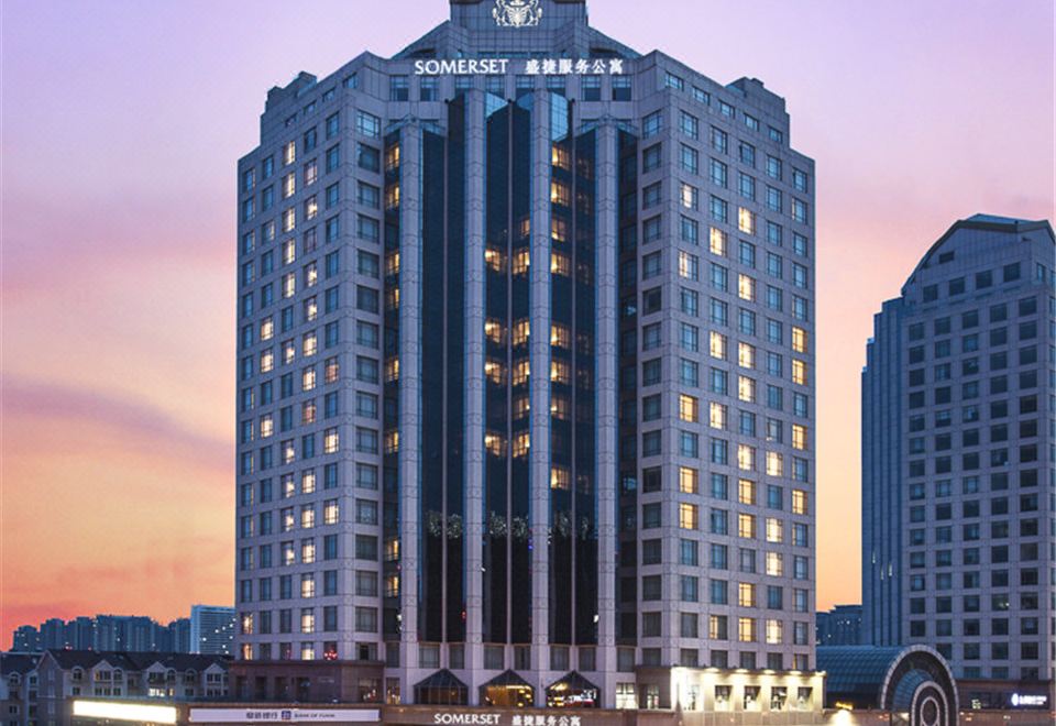 a tall hotel building in the city , surrounded by other buildings and a city street at Somerset Grand Central Dalian