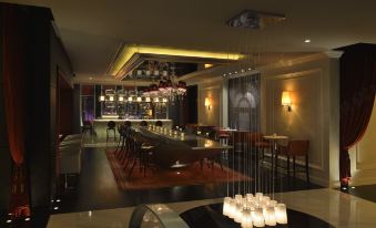 In the middle of the restaurant, there are tables and chairs, as well as an illuminated bar area at Shanghai Jinjiang Metropolo Classic East Nanjing Road Hotel
