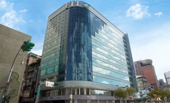 "a modern office building with a large glass window and a sign that reads "" sh "". several other buildings in the background" at Just Sleep Ximending